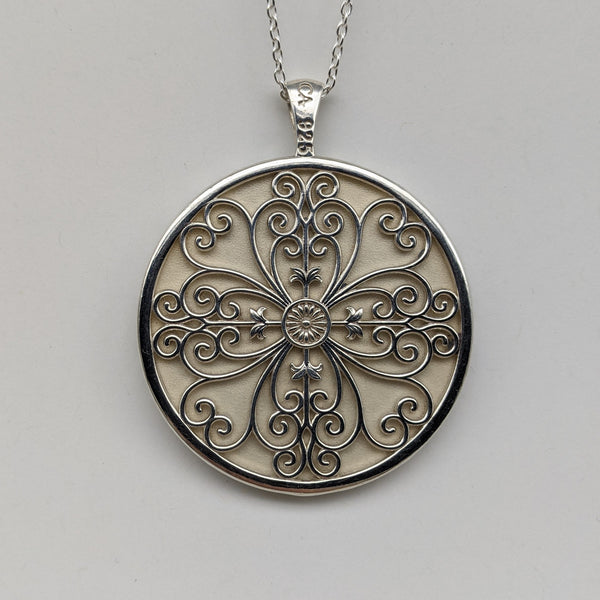 Circle pendant in sterling silver with swirled filigree in a four leaf clover design.