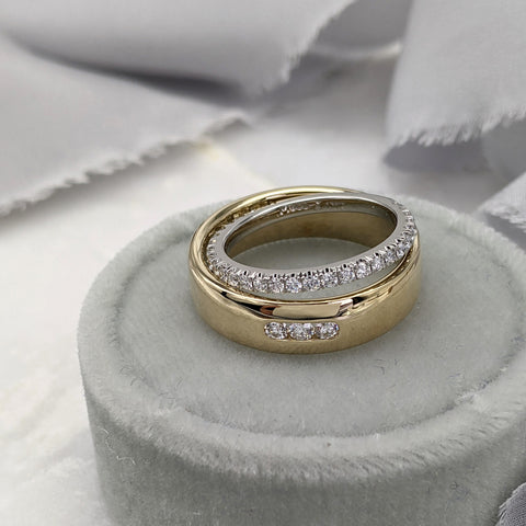 Yellow gold wedding ring with three channel set diamonds, with a platinum and diamond pavé wedding ring sitting on top of it. Both rings are in a gray velvet ring box, with gray ribbon in the background.